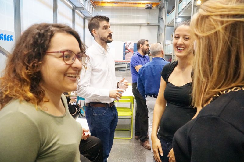 En un aula magna semicircular una persona está hablando y en los pupitres otras personas escuchando