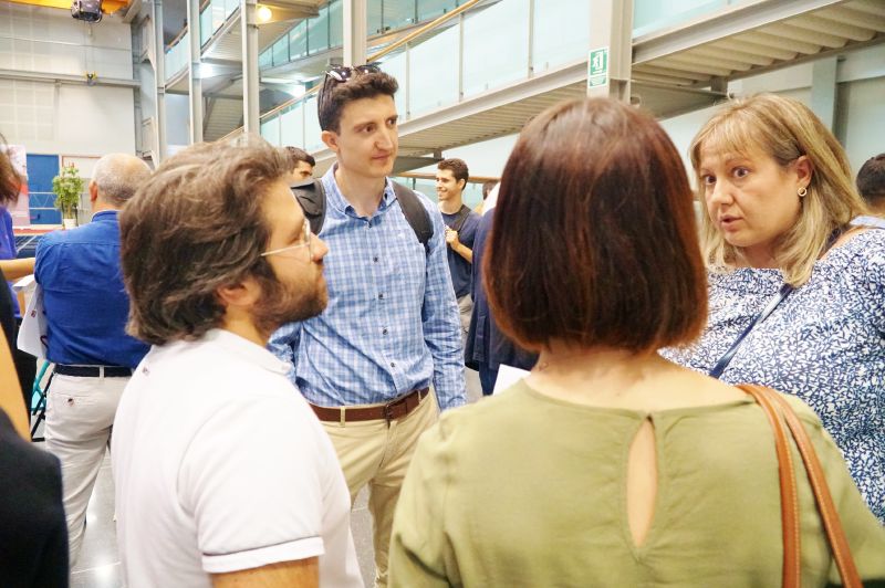 En un aula magna semicircular una persona está hablando y en los pupitres otras personas escuchando